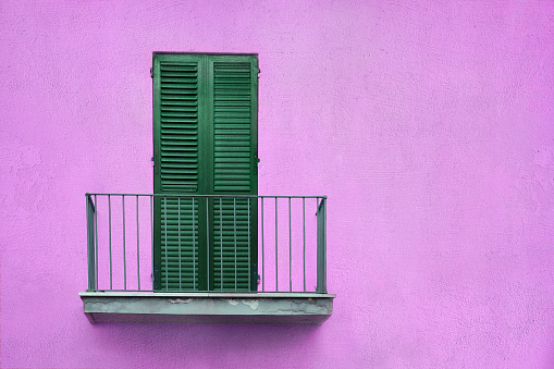 latticed wooden balcony with closed shutters on violet color wall with copy space