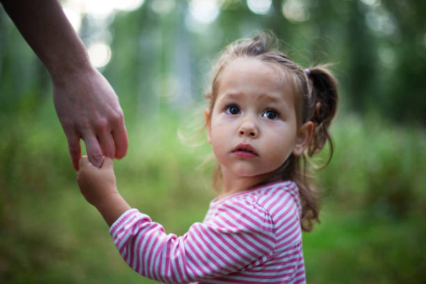 bambina carina che tiene la mano della madre - vulnerabilità foto e immagini stock