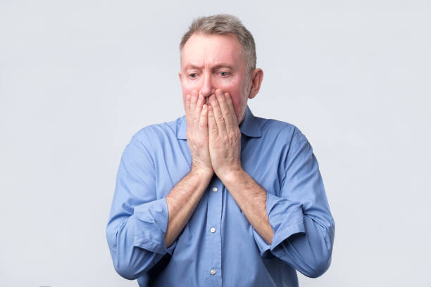istock Senior man covers mouth and looks desperately 1143557174