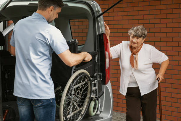 caregiver in possesso di sedia a rotelle in auto per anziana disabile con bastone da passeggio - doctor old male family foto e immagini stock