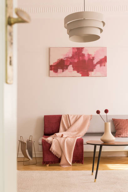 istock Poster above settee with blankets in loft interior with lamp above table with flowers. Real photo 1143563641