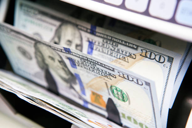 istock electronic money counter machine is counting is counting the American hundred-dollar (US dollars) banknotes, small depth of sharpness 1143571048