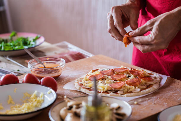 istock Making pizza, pepperoni sausage topping, close-up 1143578684