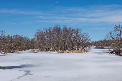 Wide angle landscape of an island in the vast St. Croix River with Wisconsin on the left shoreline and Minnesota on the right shoreline - sunny snowy winter day with beautiful blue skies
