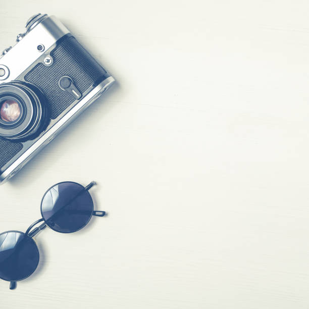istock Vintage camera with sunglasses on a wooden white background. 1143586698