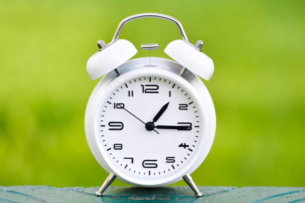 istock White alarm clock on green background. 1143591458