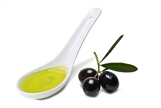 Spoonful of olive oil and black olives. stock photo