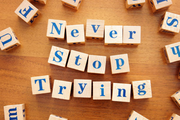 istock Never stop trying. Conceptual image with the text made from wooden cubes on a desk 1143615805