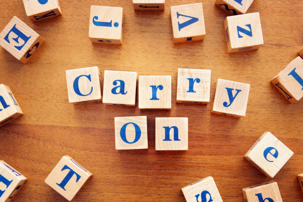 istock Carry on. Conceptual image with the text made from wooden cubes on a desk 1143616484