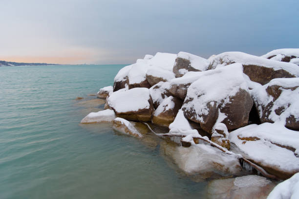 neige a recouvert des roches le long du lac michigan au coucher du soleil - beach sunrise waterbreak sea photos et images de collection