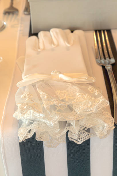 istock Ladies white gloves with lace draped cross a striped dining table 1143617505