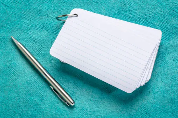 blank index cards with a pen against textured turquoise paper