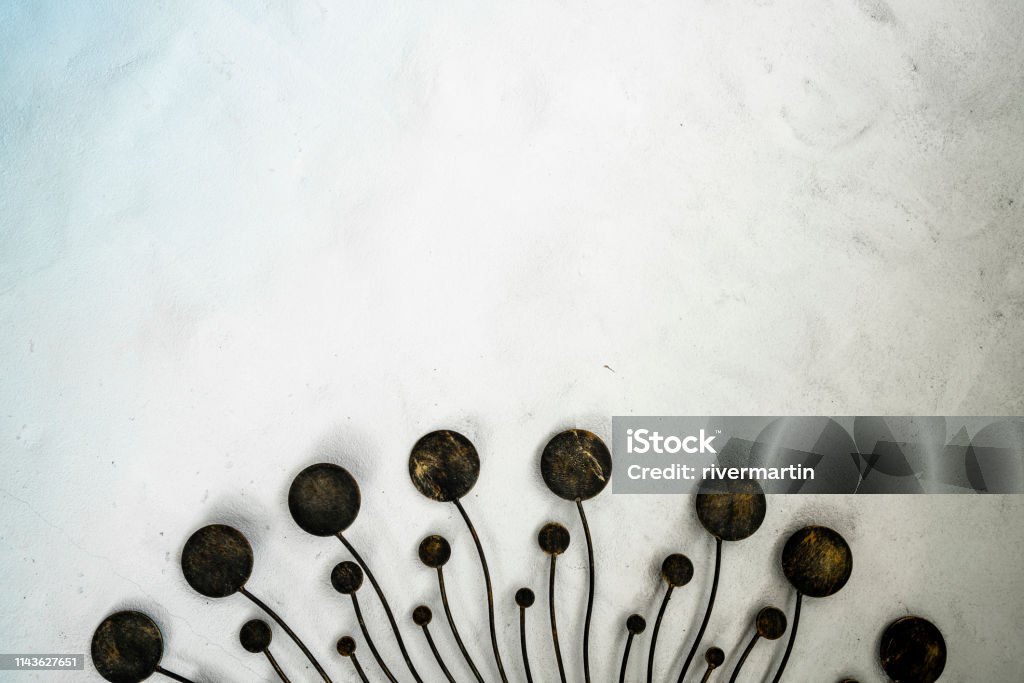 Unique-designed metal home-decor item on white rough concrete wall. Abstract Stock Photo
