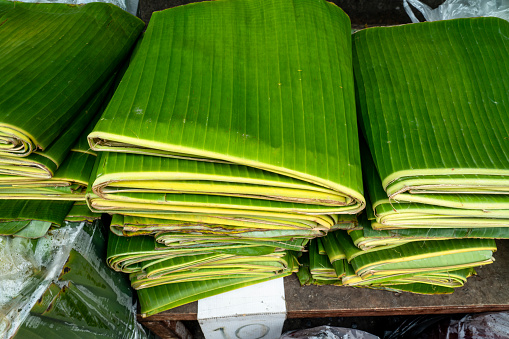 Stack of folded banana leaves displayed at a local market which will be used as food wrappers.