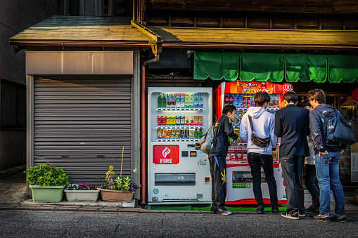 Narita, Chiba / Japan - April 13, 2019:  Unidentified Japanese teens on the street surround a beverage machine.