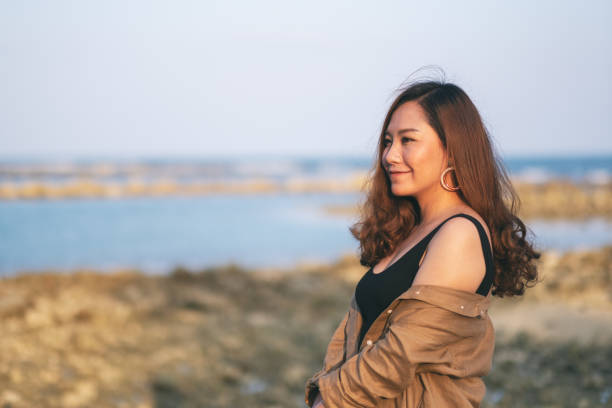 istock woman walking on the beach by the seashore 1143628859