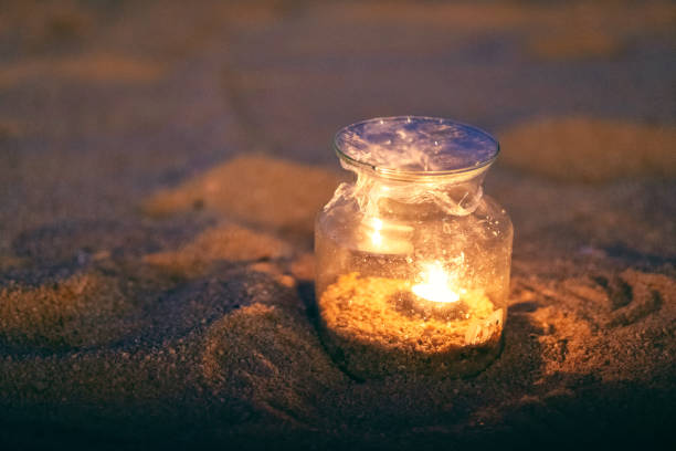istock a glass bottle candles holders on the beach at night 1143629604