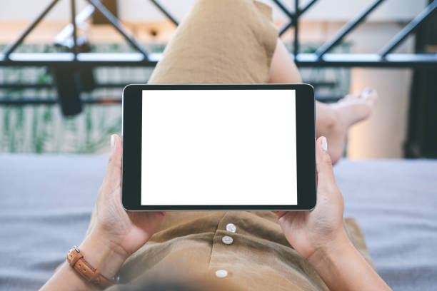istock a woman holding black tablet pc with blank white desktop screen while laying down in living room 1143630518
