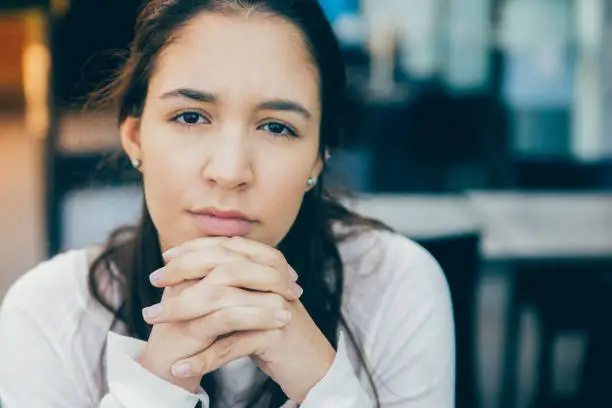 Photo of Serious face of young Latin American woman sitting at cafe