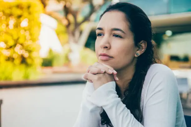 Photo of Portrait of pensive or sad young woman sitting at sidewalk cafe