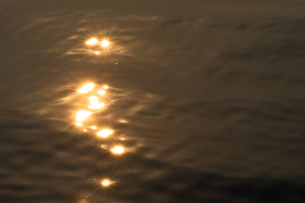 istock Wavy water surface with glittering orange sun light. 1143631026