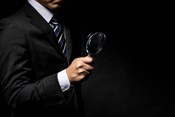 man in a suit with a magnifying glass in his hand - spy secrecy top secret mystery imagens e fotografias de stock