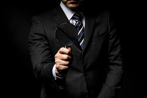 Man in a suit with a magnifying glass in his hand