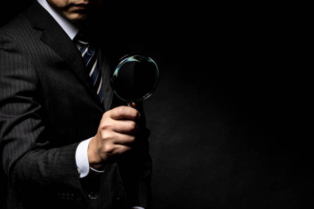 man in a suit with a magnifying glass in his hand - spy secrecy top secret mystery imagens e fotografias de stock