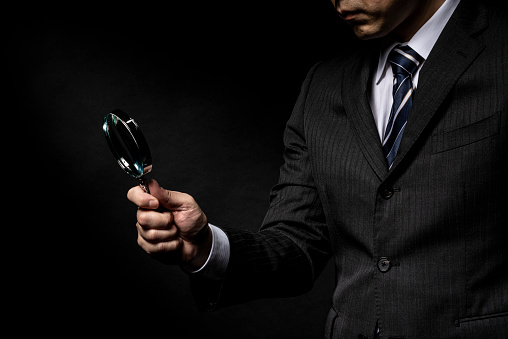 Man in a suit with a magnifying glass in his hand