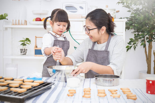 小さなアジアの女の子と彼女の母親は台所でケーキやクッキーを焼く。幸せな家族と motherâs の日のコンセプト - bread bakery women cake ストックフォトと画像
