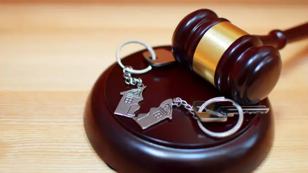 Judge gavel and key chain in shape of two splitted part of house on wooden background. Concept of real estate auction or dividing house when divorce, division of property, real estate, law system.