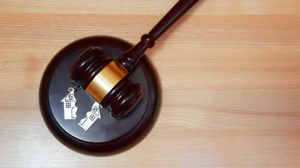 Judge gavel and key chain in shape of two splitted part of house on wooden background. Concept of real estate auction or dividing house when divorce, division of property, real estate, law system.
