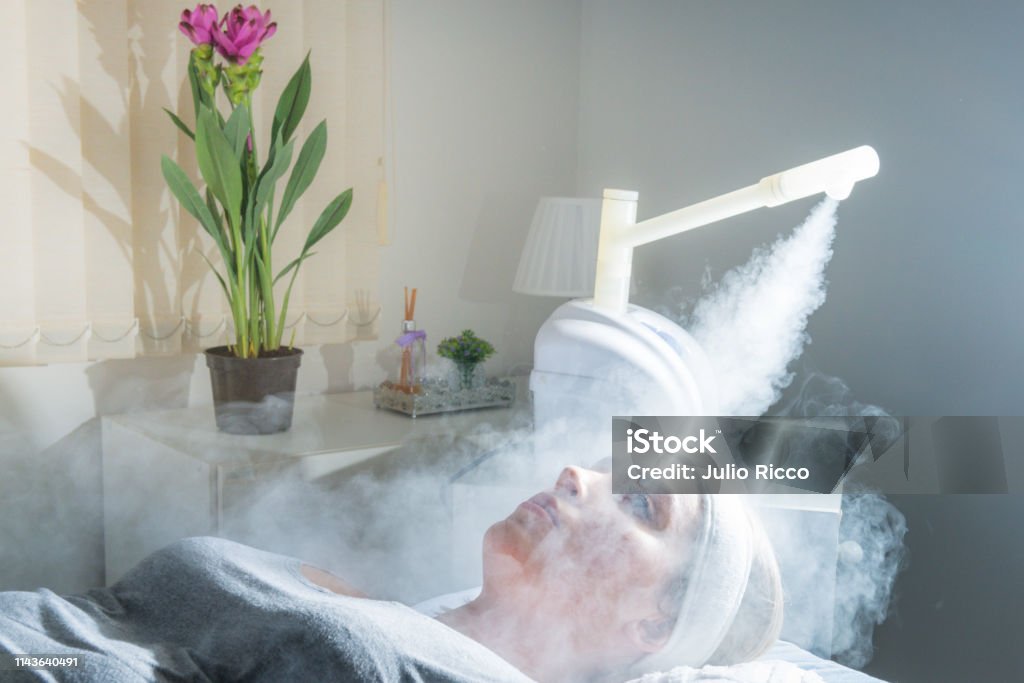 Beauty treatment of face with ozone facial steamer in beauty center. Beaultiful Blonde Girl Beauty treatment of face with ozone facial steamer in beauty center. Beaultiful Blonde Girl. Steam Stock Photo