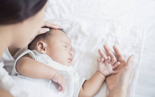 la madre controlla la temperatura di un bambino malato, il neonato aveva la febbre. concetto di festa della madre medica sanitaria - doctor asian ethnicity chinese ethnicity young adult foto e immagini stock