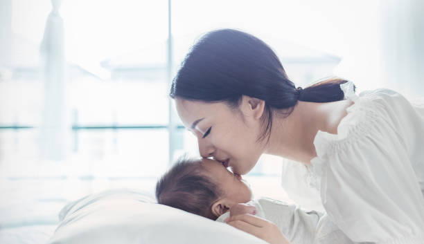 close up portrait of beautiful young asian mother kissing her newborn baby. healthcare and medical love lifestyle motherâs day concept banner - mother baby new kissing imagens e fotografias de stock