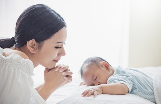Close up portrait of beautiful young asian mother with her newborn baby, copy space with bed in the hospital background. Healthcare and medical family love lifestyle nursery motherâs day concept