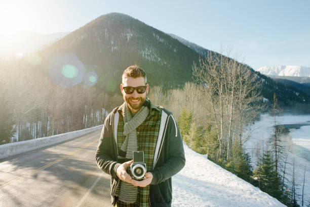 Shot of a handsome young man holding a retro camera outdoors on a winter day