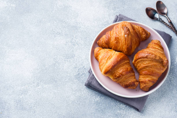 istock Breakfast croissants on a plate and a Cup of coffee on the table, copy space. 1143648129