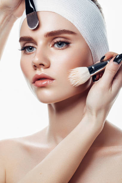 appliquer de la crème pour la peau sur le visage d’une femme - face powder photos et images de collection