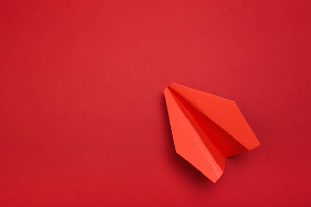 istock Flat lay of red paper plane on red background with text space. - Image 1143661924
