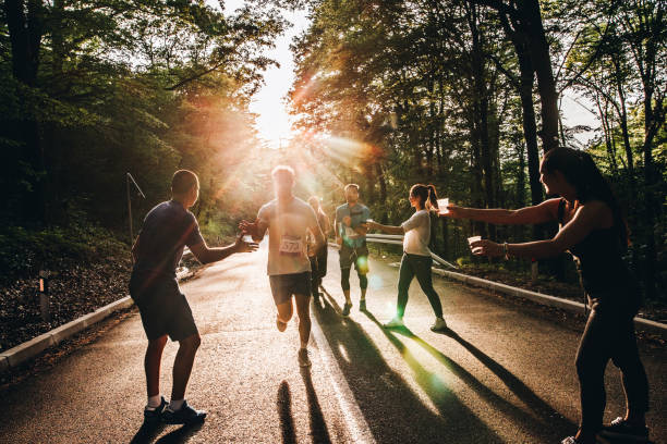 istock Group of runners taking refreshment from volunteers during a marathon race at sunset. 1143666094