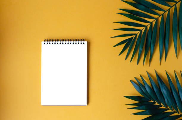 istock Notepad with palm leaves on an orange background. 1143667339