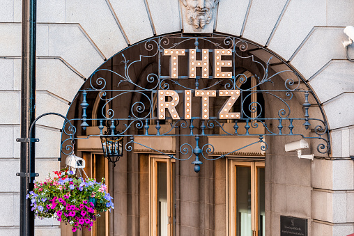 London, UK - June 22, 2018: Piccadilly Circus Regent street with closeup of sign entrance to the Ritz hotel with hanging basket flower decoration in summer and nobody