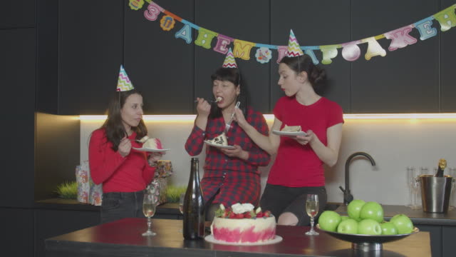 Happy women eating birthday cake in home kitchen