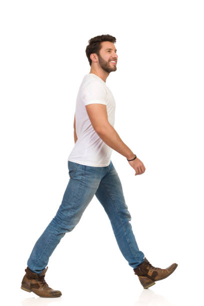 청바지와 흰색 티셔츠에 젊은 남자가 걷고 찾고 있습니다. 측면 보기 - t shirt white men jeans 뉴스 사진 이미지