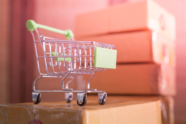 istock mini green shopping cart with cardboard boxes in background 1143681125
