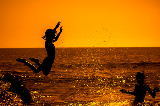 Happy young  girl jumping into the sea.