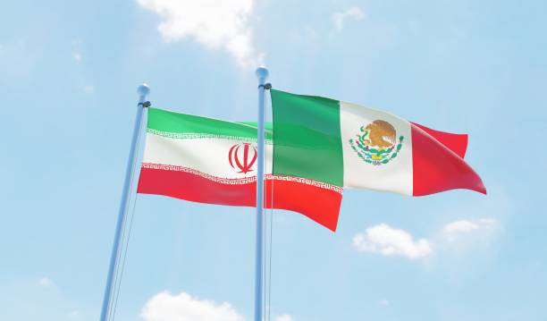 istock Mexico and Iran, two flags waving against blue sky 1143689830
