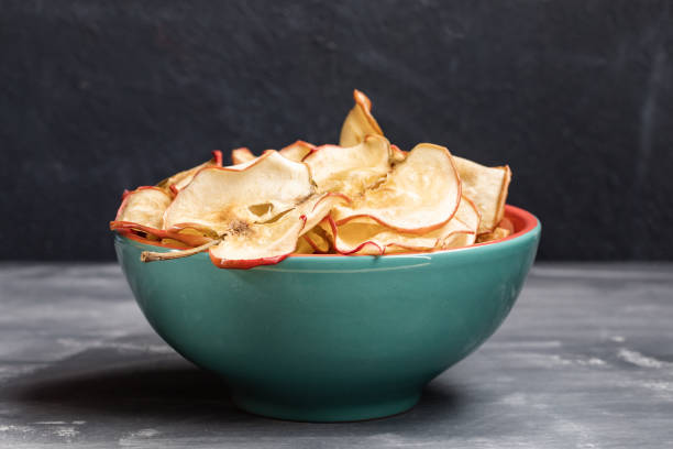 istock Close-up one turquoise ceramic bowl with apple chips on dark grey background. 1143692035