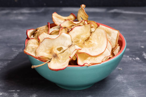 istock Close-up apple chips in turquoise bowl on dark grey background. 1143692036